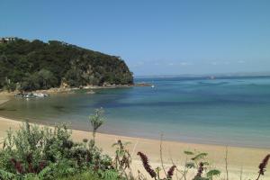 a beach with a small island in the water at Whatuwhiwhi TOP 10 Holiday Park in Tokerau Beach