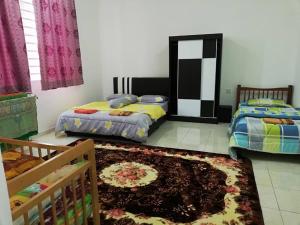 a bedroom with two beds and a rug at Faeyz Homestay Melaka in Melaka