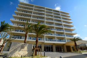 a large white building with palm trees in front of it at Lieta Nakayama in Nago