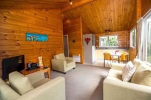 a living room with wood paneled walls and a fireplace at Tatahi Lodge Beach Resort in Hahei