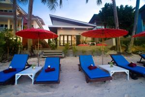 eine Gruppe von Stühlen und Sonnenschirmen am Strand in der Unterkunft The Florist Resort in Mae Nam