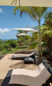 a patio with two beds and an umbrella at Bois Joli in Mahe