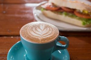 a cup of coffee on a plate with a sandwich at The Yurts at Margo's Garden, Kiroro in Shiribeshi