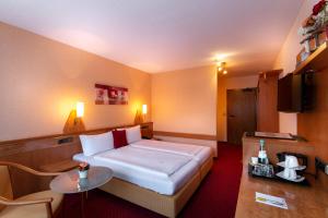 ein Hotelzimmer mit einem Bett und einem Tisch in der Unterkunft Hotel Zum Rosengarten in Darmstadt