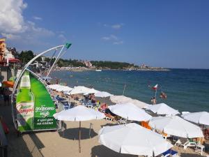 a beach with white umbrellas and people on the water at Levante apartments in Nesebar