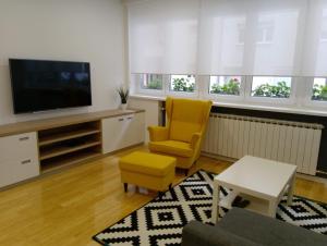 a living room with a television and a yellow chair at ZagrebFun in Zagreb