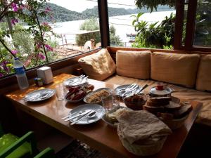 una mesa con platos, utensilios y comida. en Cennet Pansiyon, en Kaleucagız