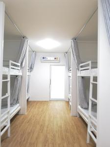 a room with white bunk beds and a door at CuteinNan Hostel in Nan
