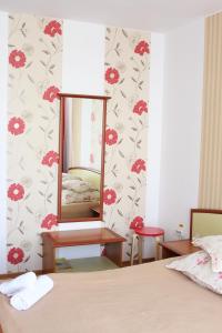 a bedroom with a mirror on a wall with red flowers at Vila Meteor in Cluj-Napoca