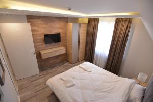 a bedroom with a white bed and a television at Milmari Resort Premier 47 in Kopaonik +31 photos