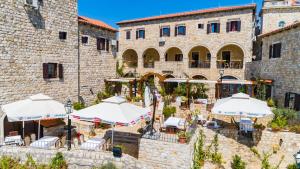 an old stone building with tables and umbrellas at Hotel Palata Venezia in Ulcinj