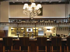 duży bar z krzesłami i żyrandolem w obiekcie Fox and Grapes w Londynie