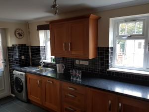 een keuken met houten kasten en een zwart aanrecht bij Spacious Swindon 5 bedroom house - sleeps up to 10 in Swindon