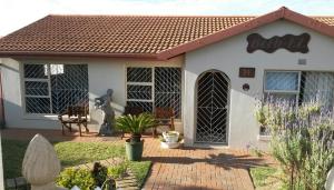 a small white house with a statue in the yard at Beth-El in Mossel Bay