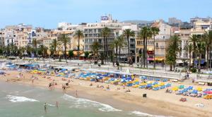 a beach with people and umbrellas and the ocean at Hotel Subur in Sitges