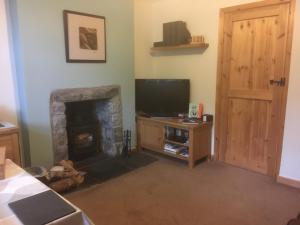 a living room with a television and a fireplace at Garth Engan Private Self Contained B&B with Garden Area in Llanbedr
