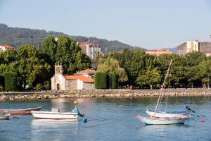 three boats in a river with a city in the background at Hotel Airiños 3* in Cangas de Morrazo