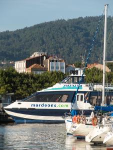 a large boat docked in the water with other boats at Hotel Airiños 3* in Cangas de Morrazo