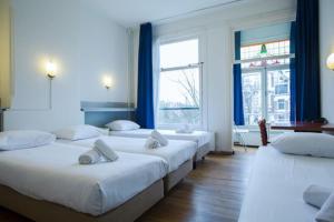 Habitación con 4 camas y cortinas azules. en Hotel Titus City Centre, en Ámsterdam