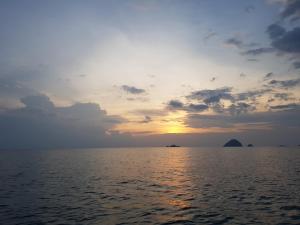 a sunset over the water with islands in the distance at Ombak Dive Resort Perhentian Island in Perhentian Islands