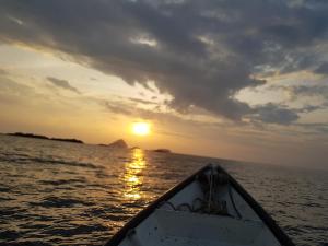 a boat in the ocean with the sun setting at Ombak Dive Resort Perhentian Island in Perhentian Islands