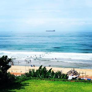 a group of people on a beach near the ocean at Ansteys Beach Self Catering Apartments in Durban