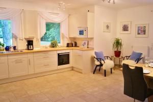 a kitchen with white cabinets and a table and chairs at Ferienhaus Wahlers in Bispingen