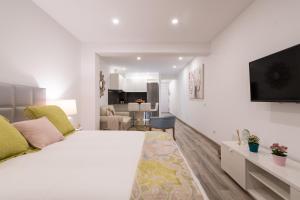 a white bedroom with a large bed and a living room at Sony Cosi Loft Canteras in Las Palmas de Gran Canaria