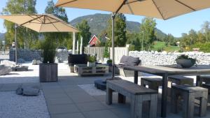 a patio with tables and benches and an umbrella at Løvheim Gjestehus in Sauland