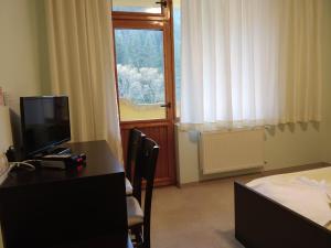 um quarto com uma secretária, uma televisão e uma janela em Hotel Restaurant Popini Laki em Yagodina