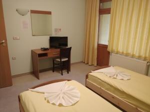 a room with two beds and a desk and a mirror at Hotel Restaurant Popini Laki in Yagodina