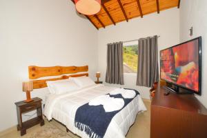 a bedroom with a bed and a flat screen tv at Maison Bleue Suites in Monte Verde