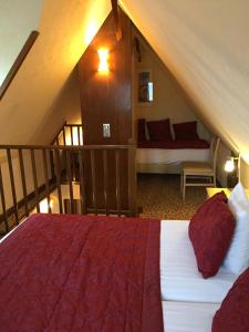 um quarto no sótão com uma cama e uma escada em Hôtel la Croix Blanche em Monte Saint-Michel
