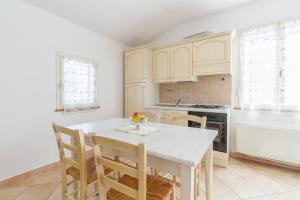 - une cuisine avec des placards blancs, une table et des chaises dans l'établissement Agriturismo Valle Martina, à Saturnia