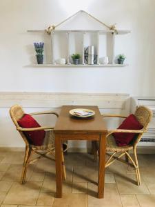 レッチェにあるDimora Il Tiglio- mini appartamentiのダイニングルームテーブル、椅子2脚(赤いクッション付)
