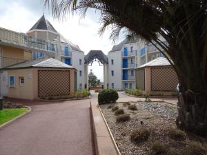 a street in front of a building with a palm tree at Appartement vue sur golf in Talmont