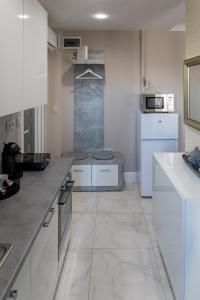 uma cozinha com armários brancos e uma bancada em Derin Apartman em Debrecen