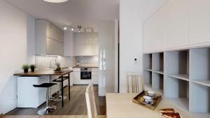 a kitchen with white cabinets and a table in it at Na Szancach 8E TectumApartments in Wrocław