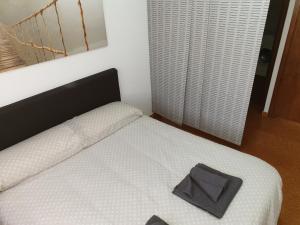 ビリャヌアにあるApartamento Gonzaloの白いベッド(黒いヘッドボードとグレーの袋付)