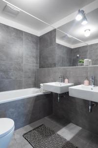 een badkamer met 2 wastafels, een bad en een toilet bij Apartment Invalidovna with FREE parking in Praag