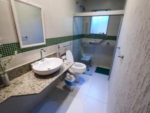 uma casa de banho com um lavatório e um WC em Pousada das Garças em Saquarema
