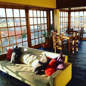a couch with pillows on it in a room with windows at Hosteria Kupanaka in Ushuaia
