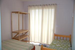1 dormitorio con 1 cama y una ventana con cortinas en Residencial Oceano Azul en Itapoa