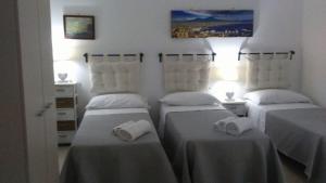 - 3 lits dans une chambre dotée de draps blancs et de serviettes dans l'établissement Casa Luna, à Naples
