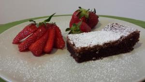 a piece of cake and strawberries on a plate at B&B Il Guado in Voghenza