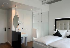 a bedroom with a bed and a mirror and a sink at INNSiDE by Meliá Düsseldorf Hafen in Düsseldorf