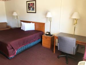 Kewanee的住宿－Kewanee Motor Lodge，酒店客房配有一张床、一张桌子和一把椅子。