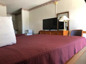 Habitación de hotel con cama y TV de pantalla plana. en Kewanee Motor Lodge en Kewanee