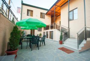 eine Terrasse mit Stühlen und einem Tisch mit einem grünen Sonnenschirm in der Unterkunft Hotel Elegant 2 in Tbilisi City