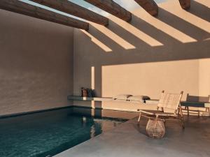 a room with a pool and a chair next to a swimming pool at Vais Luxury Villas in Agios Nikolaos